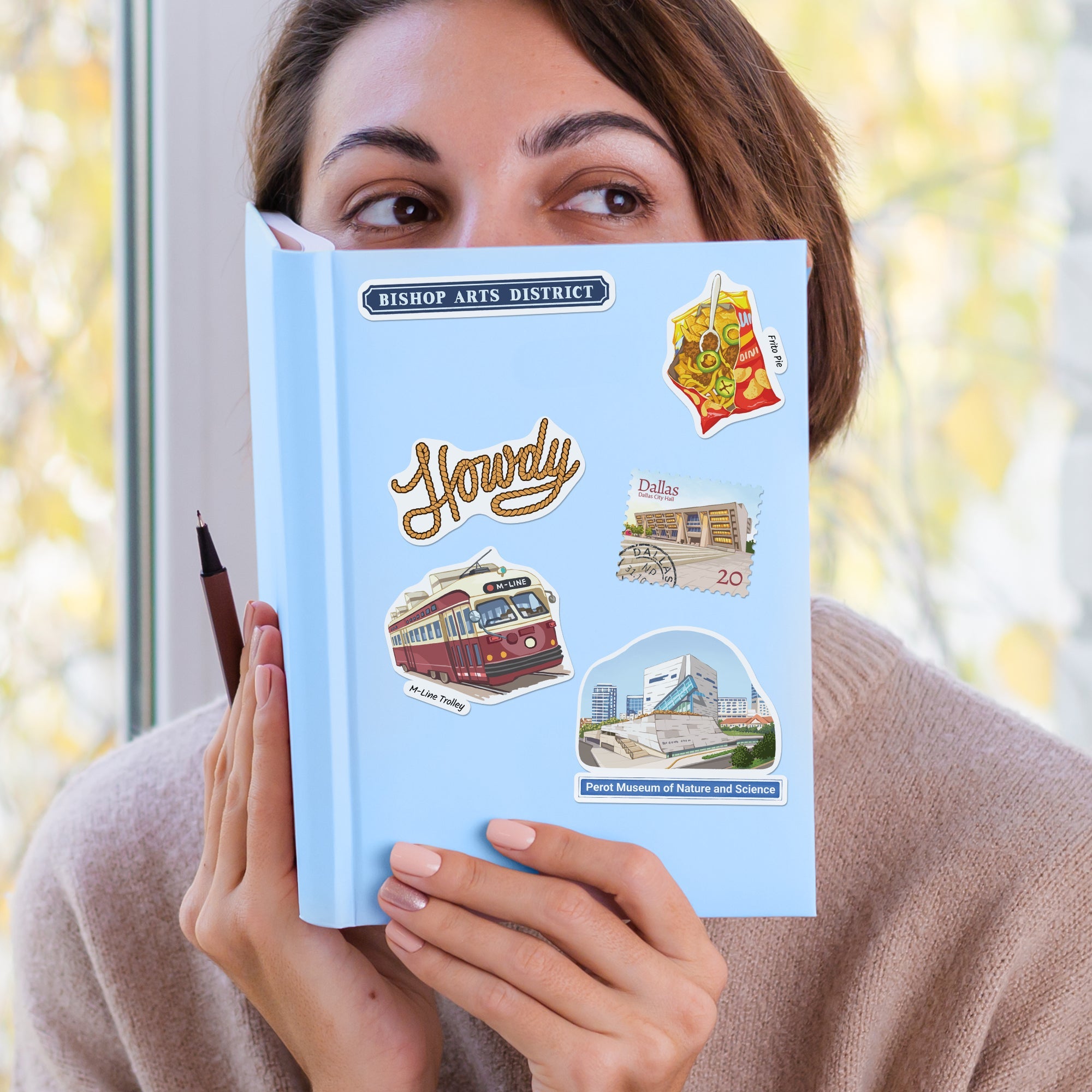 Travel stickers decorating a journal held up to the camera, from Navy Peony's newest destination sets