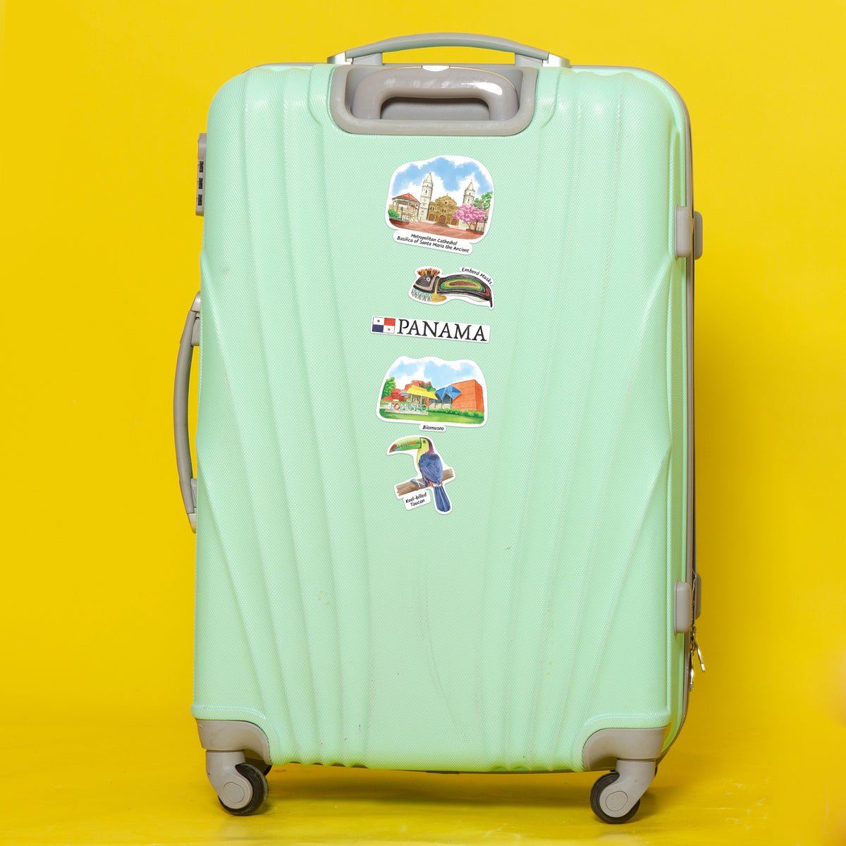 A mint green hard-shell spinner suitcase with travel stickers, including a Panama sticker, set against a solid bright yellow background.