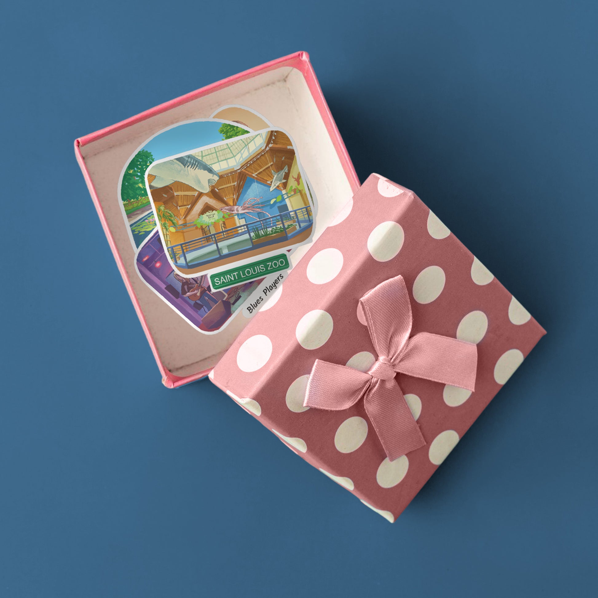 Open pink polka-dot gift box holding Saint Louis Zoo and blues musician die-cut stickers.