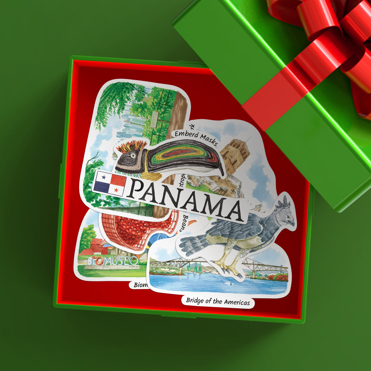 A gift box with a red interior displaying a Panama-themed collage sticker or decal featuring landmarks, the Panama flag, and the word PANAMA. A green gift box with a red ribbon is partially visible in the upper right on a green background.