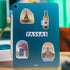 Blue tablet with Santorini stickers of a sunset bell tower, a wine bottle, 'Yassas' and a blue door