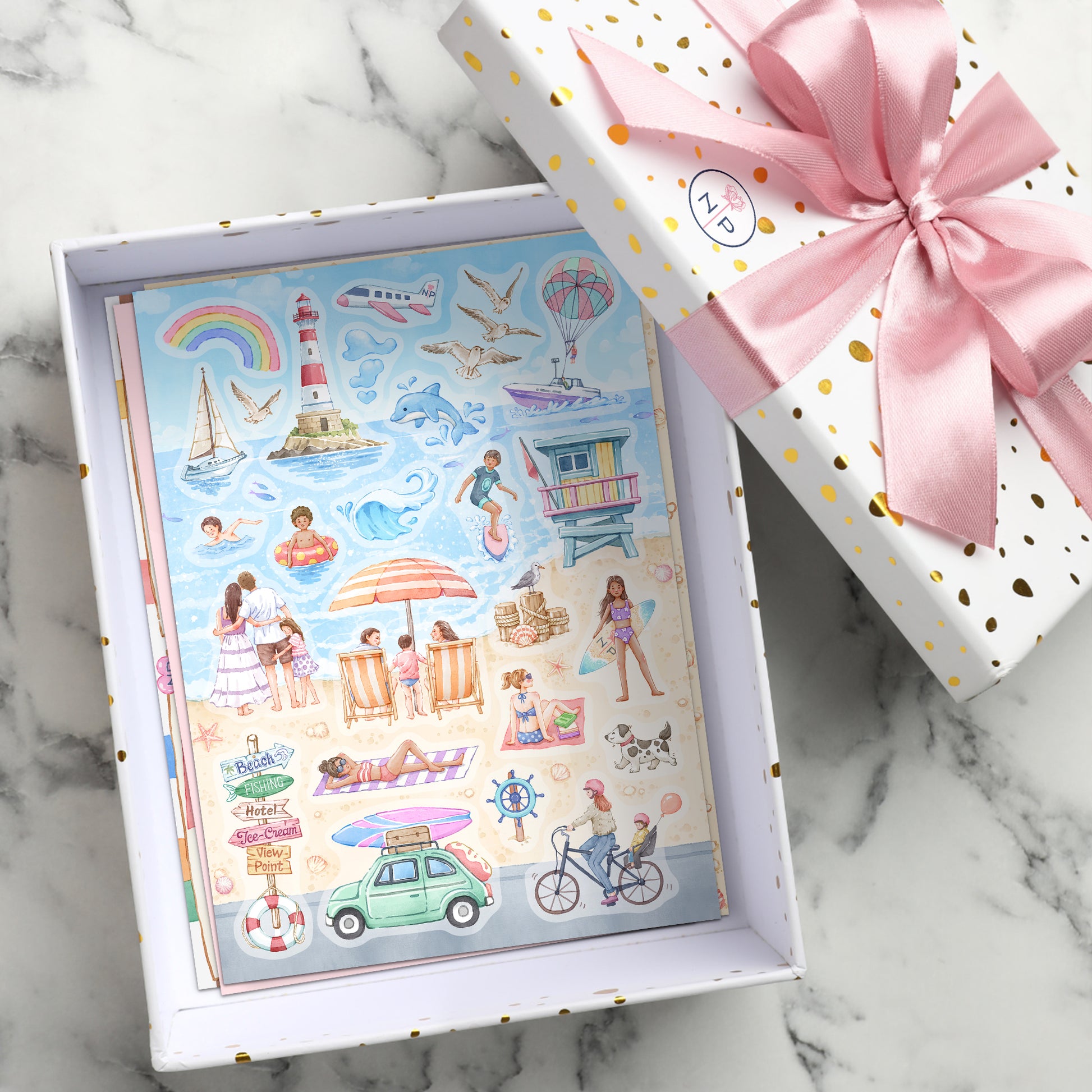 A seaside sticker sheet with swimmers, a lighthouse and a rainbow inside a white gift box with a pink bow