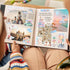 Beach stickers and photos on an open scrapbook spread held on a lap, with a mint car and a rainbow