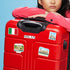 Italian flag, "MILAN" and Doge’s Palace stickers on a red hard-shell suitcase a woman leans on
