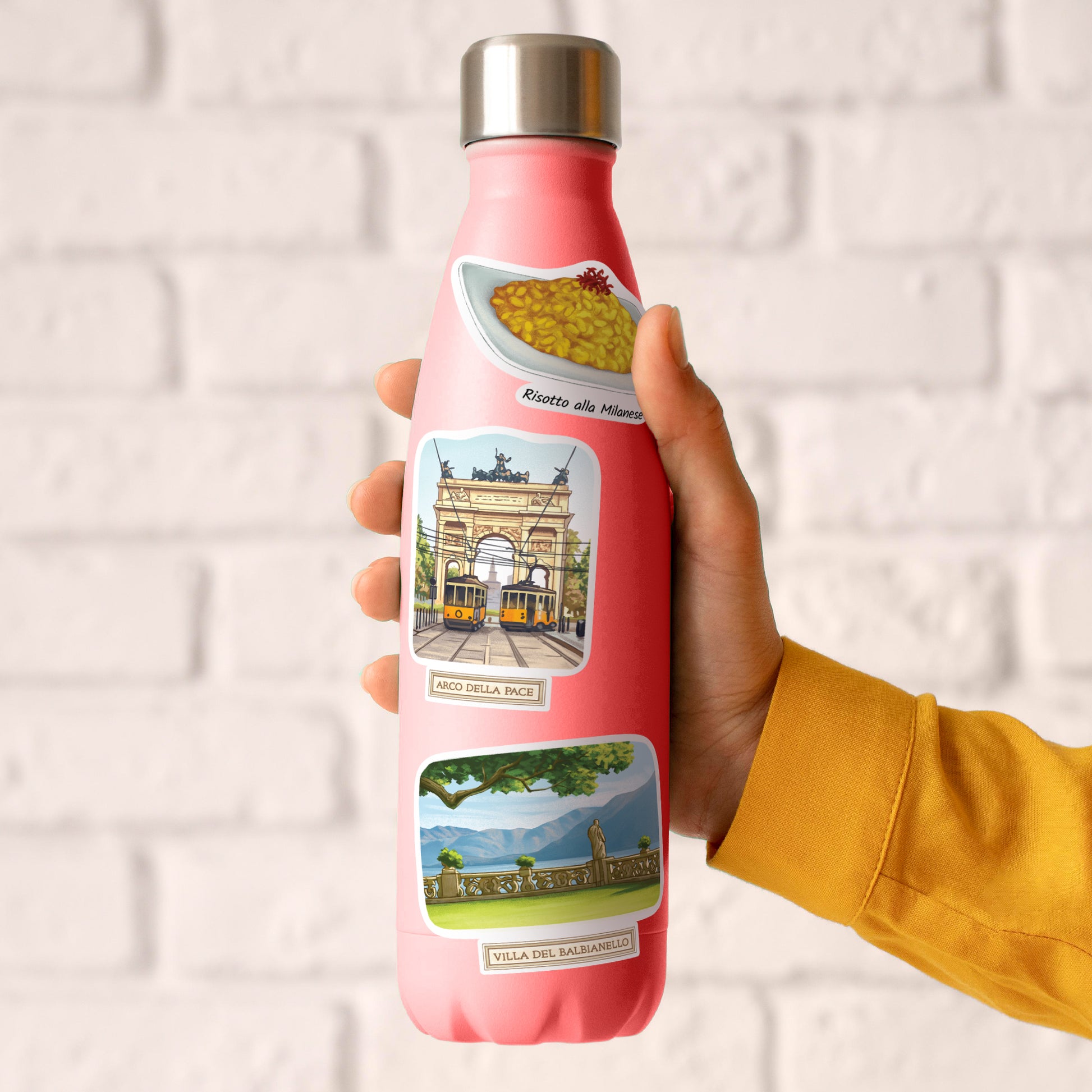 Risotto, Arco della Pace and Villa del Balbianello stickers on a pink water bottle held in one hand