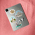 Duomo di Milano, Sforzesco Castle and gondola stickers on a silver tablet back beside earbuds