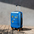 Fenway Park and 'Boston' stickers on a bright blue hardshell suitcase on a wooden deck