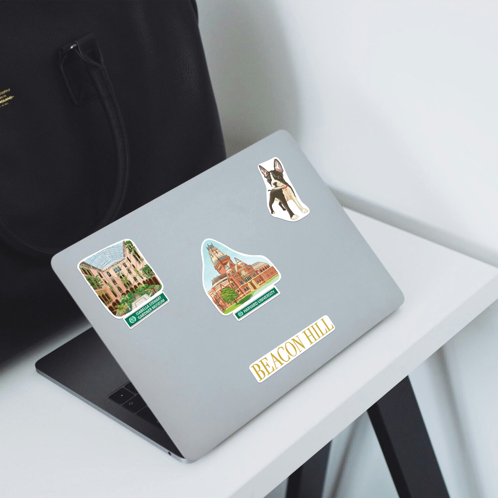 Boston terrier, Gardner Museum and 'Beacon Hill' stickers on a silver laptop on a white desk
