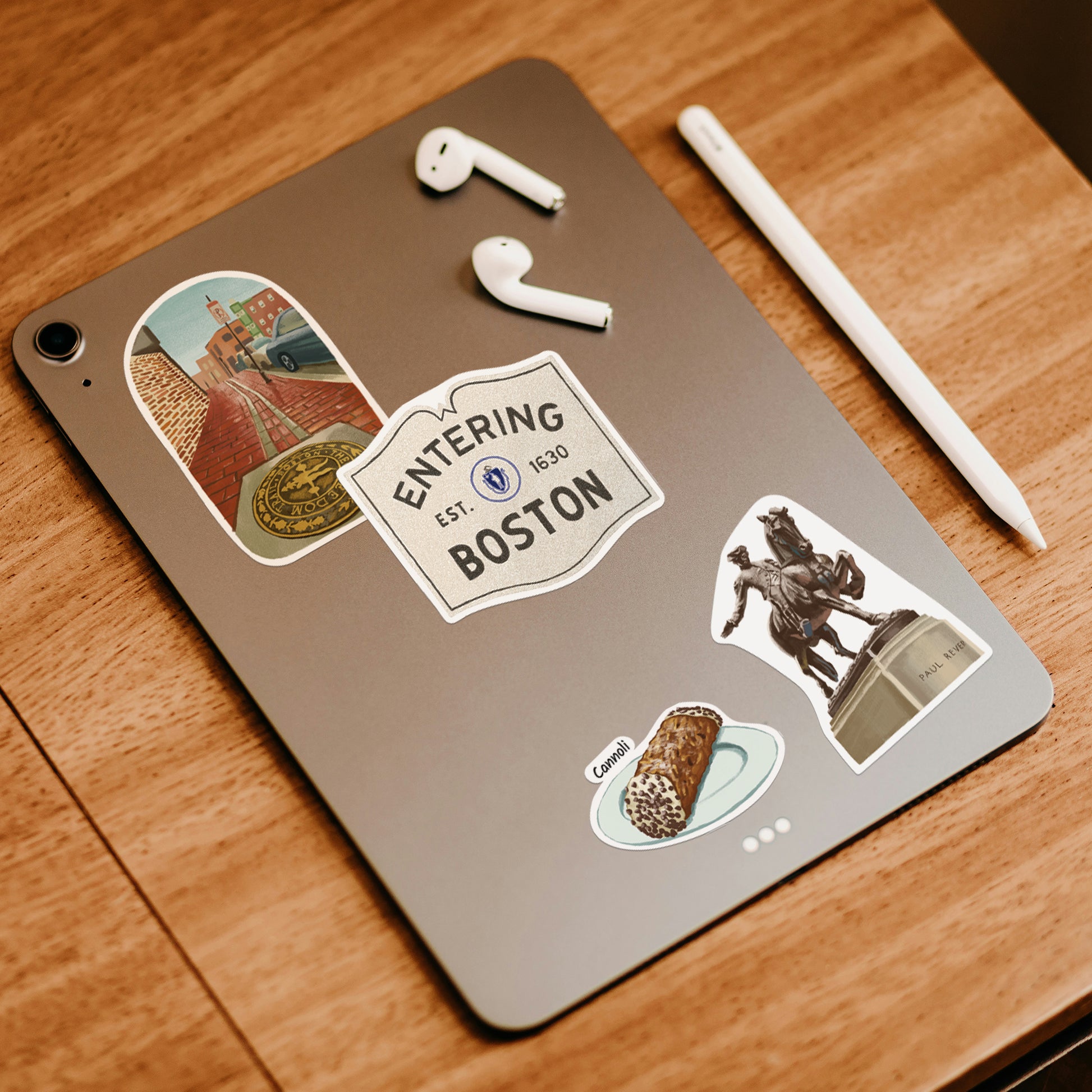 Freedom Trail, 'Entering Boston' sign, Paul Revere statue and cannoli stickers on a tablet with earbuds