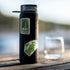 A Boston stamp sticker and a green state map sticker on a black water bottle beaded with water