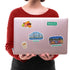 Miami Skyline, Art Deco District and "Ocean Dr" stickers on a silver laptop held against a red jumper