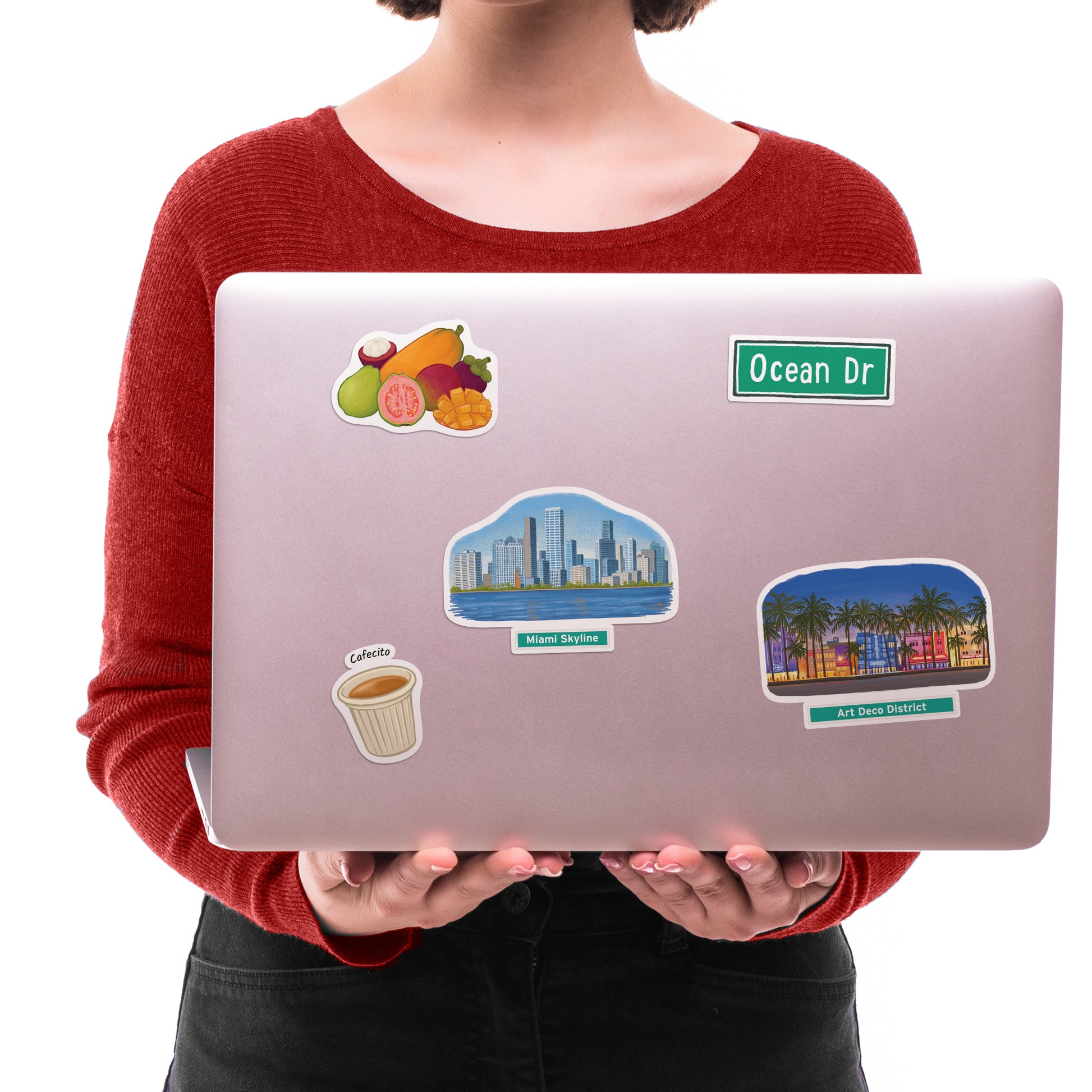 Miami Skyline, Art Deco District and "Ocean Dr" stickers on a silver laptop held against a red jumper