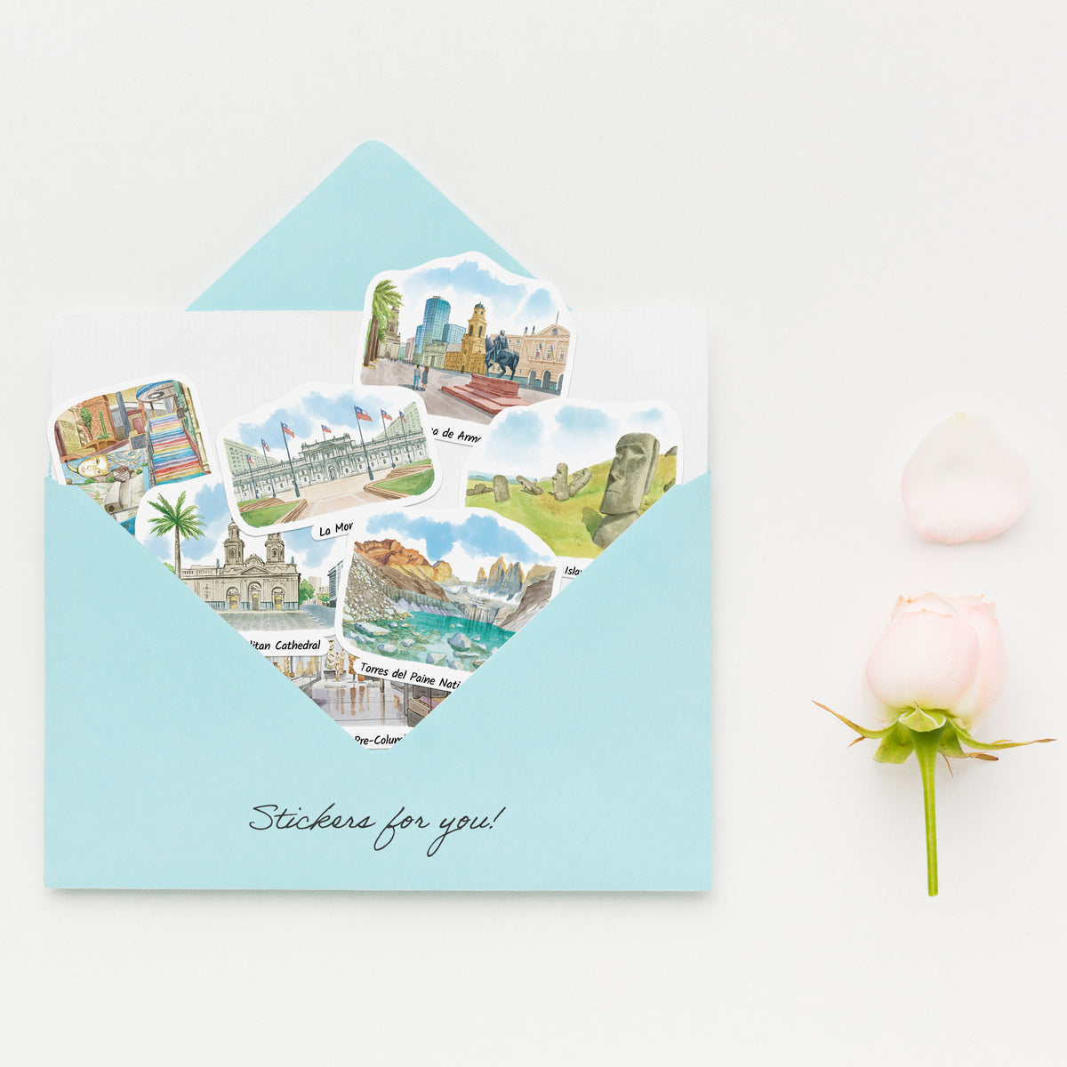 A light blue envelope on a white background with several illustrated travel sticker cutouts emerging from the front. The envelope has the words 'Stickers for you!' printed at the bottom.